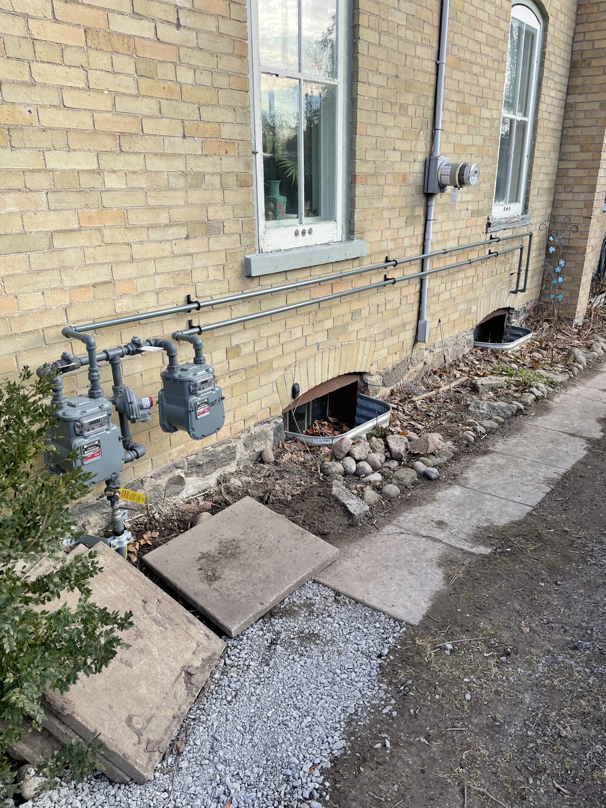 Two gas meters and exterior piping on a brick wall